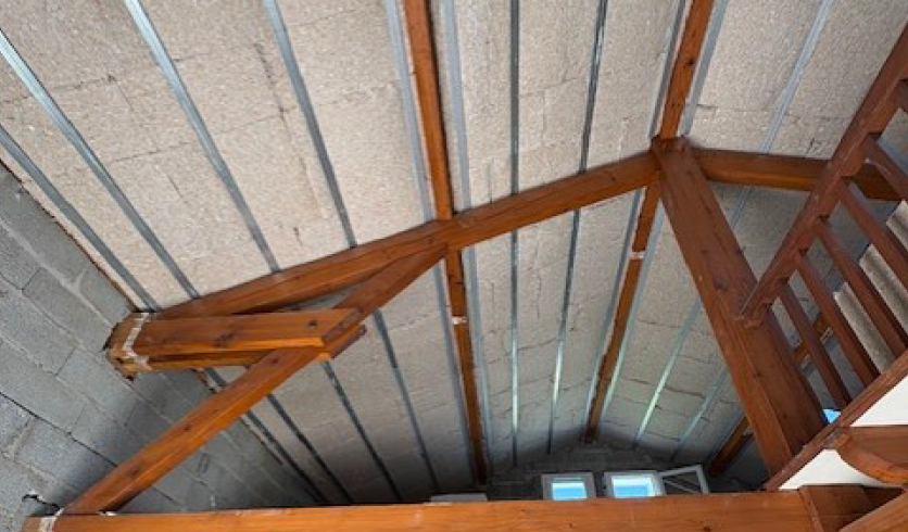 Jonction soignée entre le nouveau plafond rampant en plâtre et les vieilles poutres apparentes